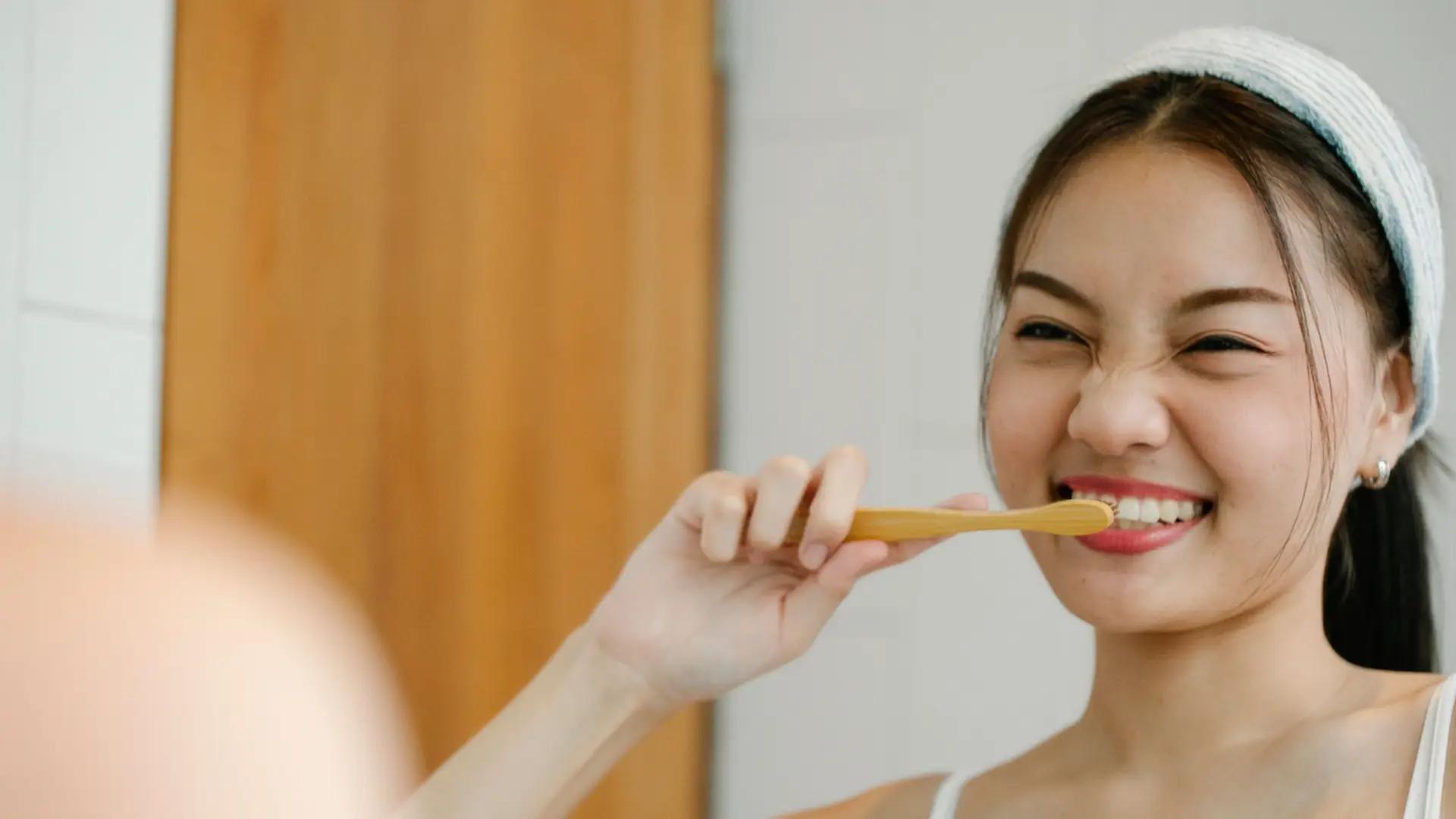 Cô gái chải răng và mỉm cười trước gương