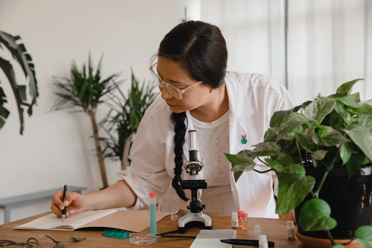 Nhà khoa học ghi chép kết quả cạnh kính hiển vi